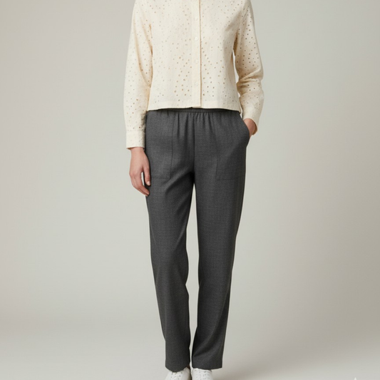 Person wearing a beige jacket and gray pants on a plain background